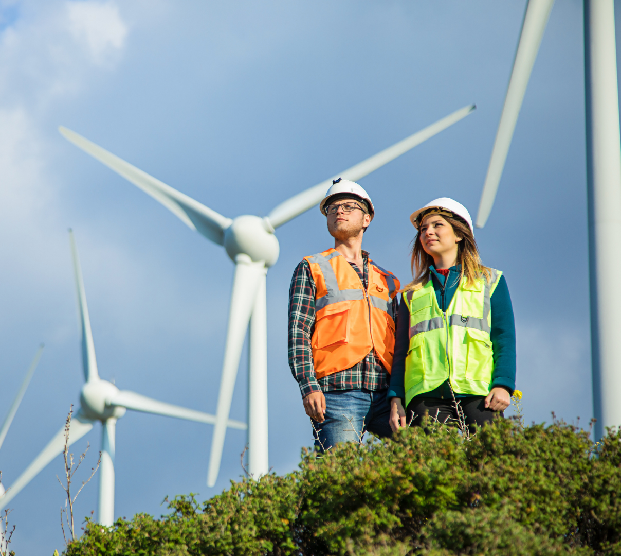 Two people with safety suit and wind turbines behind