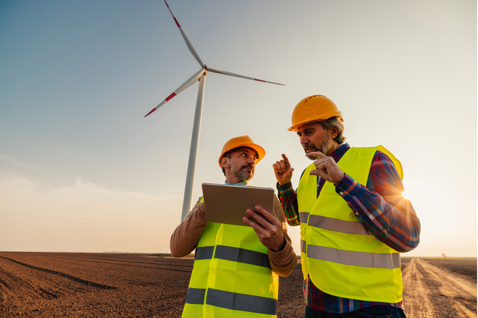 Two men with a tablet and a wind turbine